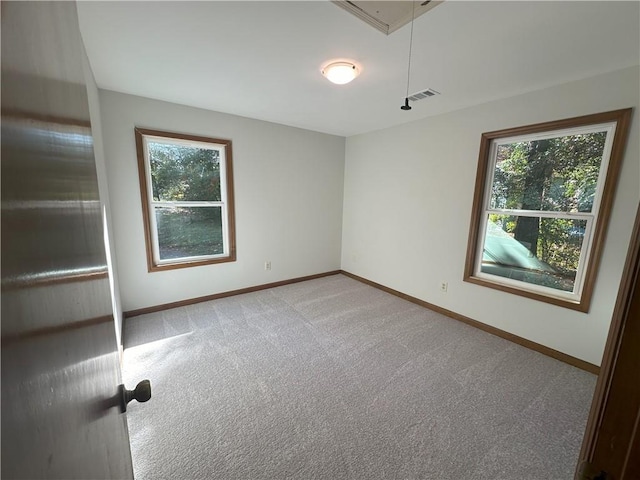 carpeted empty room featuring visible vents, a healthy amount of sunlight, attic access, and baseboards