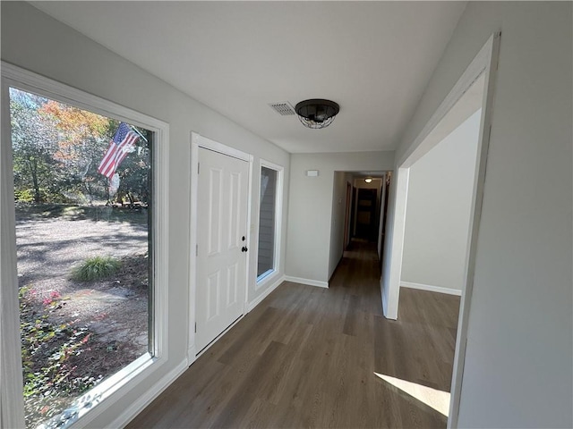 hall featuring visible vents, plenty of natural light, baseboards, and wood finished floors