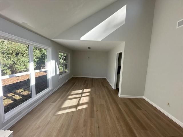 empty room with vaulted ceiling, baseboards, and wood finished floors