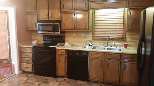 kitchen featuring black appliances, a sink, light countertops, and brown cabinets