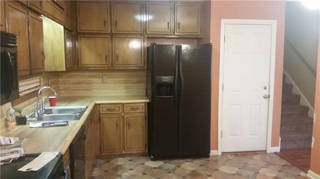 kitchen featuring stainless steel appliances, brown cabinets, light countertops, and a sink