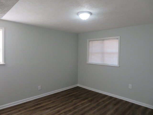 unfurnished room with dark wood-type flooring, a textured ceiling, and a healthy amount of sunlight