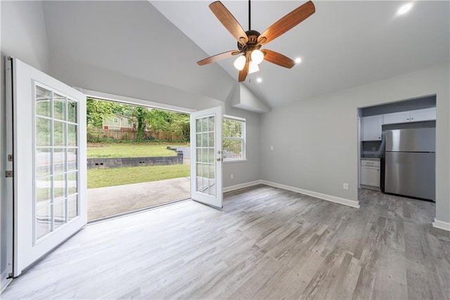 unfurnished living room featuring light wood-type flooring, a ceiling fan, high vaulted ceiling, and baseboards