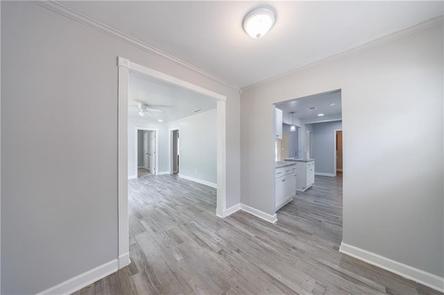 corridor with baseboards, light wood-style flooring, and crown molding