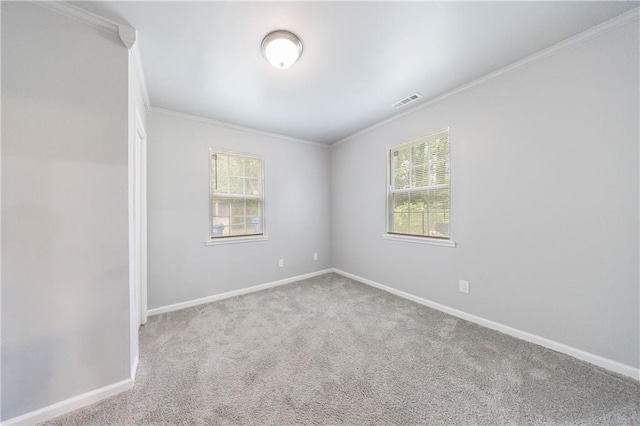 carpeted spare room with visible vents, plenty of natural light, crown molding, and baseboards