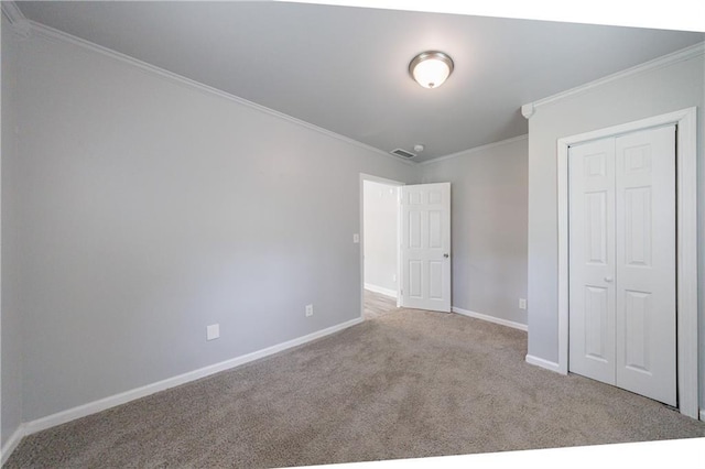 unfurnished bedroom featuring a closet, crown molding, visible vents, baseboards, and carpet floors