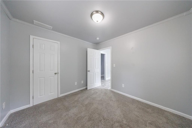unfurnished bedroom featuring carpet, visible vents, crown molding, and baseboards