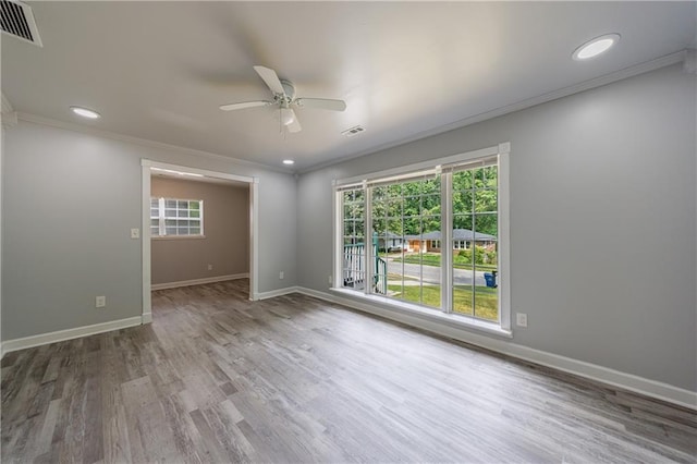 empty room with wood finished floors, visible vents, ceiling fan, and a healthy amount of sunlight