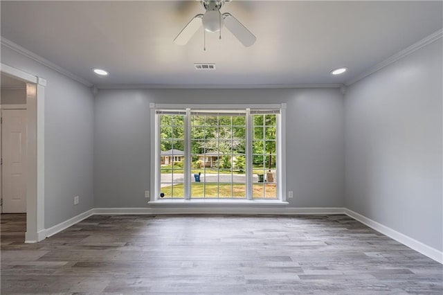 unfurnished room featuring wood finished floors, ceiling fan, baseboards, visible vents, and crown molding