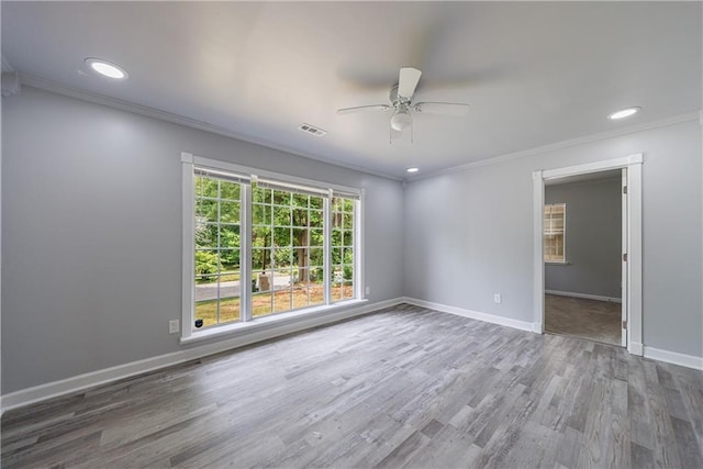 unfurnished room featuring ceiling fan, crown molding, visible vents, baseboards, and wood finished floors