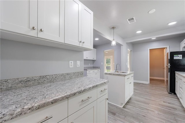 kitchen featuring recessed lighting, a sink, and white cabinets