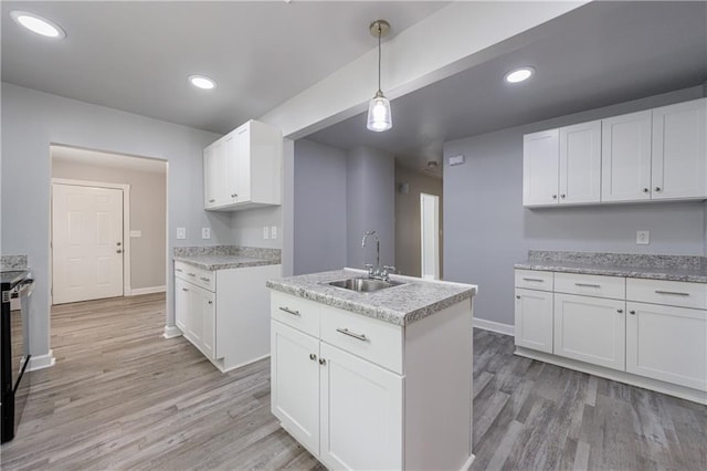 kitchen featuring a sink, baseboards, white cabinetry, and light wood-type flooring