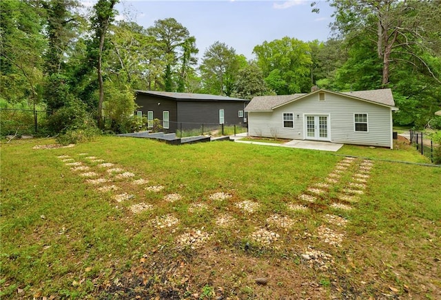 rear view of property featuring a lawn, a fenced backyard, french doors, and a patio area