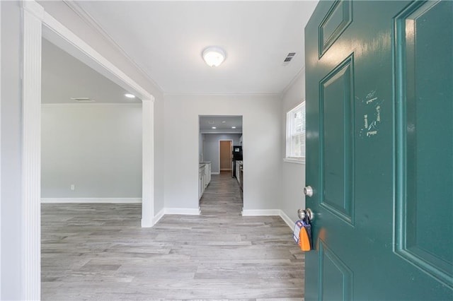 foyer with visible vents, ornamental molding, light wood-style flooring, and baseboards