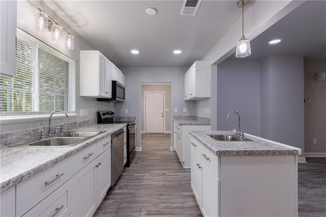 kitchen with visible vents, stainless steel appliances, light wood finished floors, and a sink