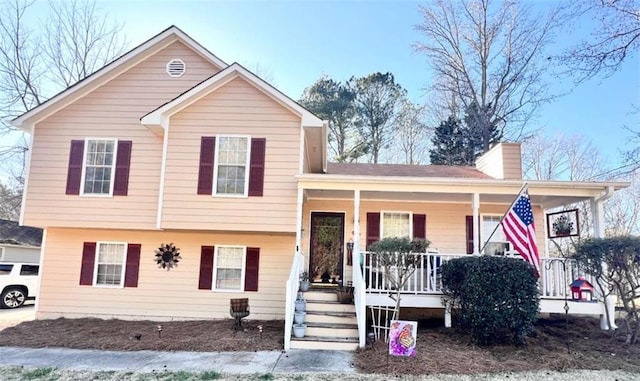 tri-level home featuring covered porch and a chimney