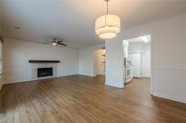 unfurnished living room with ceiling fan, ornamental molding, and light hardwood / wood-style flooring