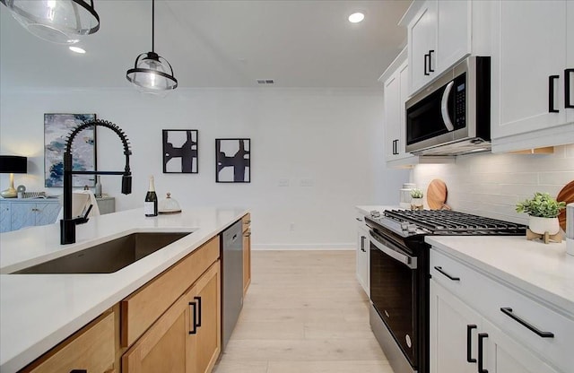 kitchen featuring appliances with stainless steel finishes, sink, light brown cabinets, decorative light fixtures, and white cabinets