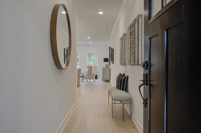 hallway with light hardwood / wood-style floors and crown molding