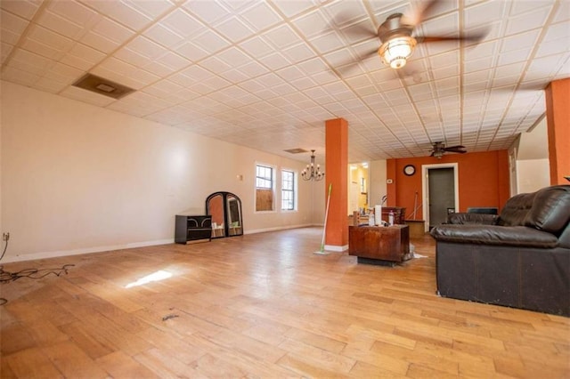 unfurnished living room with ceiling fan with notable chandelier and light hardwood / wood-style floors