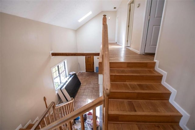 stairs featuring lofted ceiling with skylight