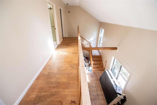 hall with lofted ceiling and light hardwood / wood-style flooring