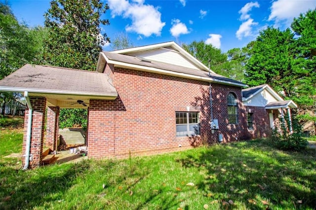 view of side of property with a lawn and ceiling fan