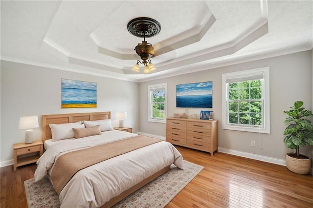 bedroom featuring ornamental molding, light hardwood / wood-style floors, and a raised ceiling