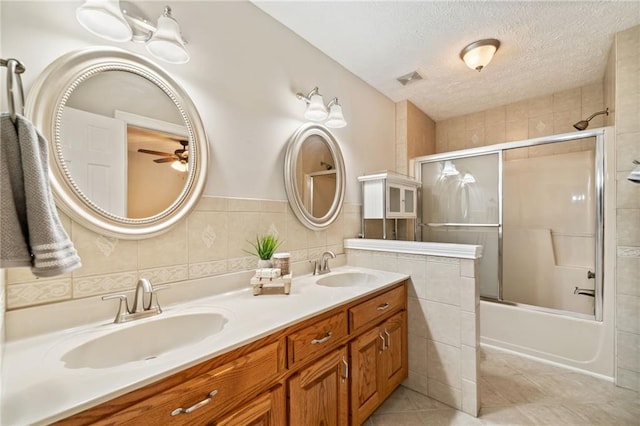 bathroom featuring tile patterned floors, enclosed tub / shower combo, tile walls, a textured ceiling, and vanity