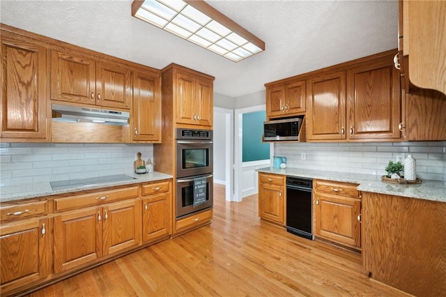 kitchen with light hardwood / wood-style flooring, stainless steel appliances, backsplash, and light stone countertops