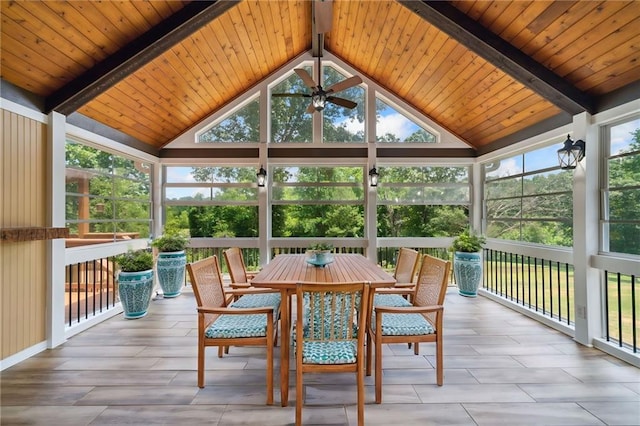 unfurnished sunroom with ceiling fan, vaulted ceiling with beams, and a wealth of natural light