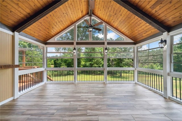 unfurnished sunroom featuring ceiling fan, vaulted ceiling with beams, and a wealth of natural light