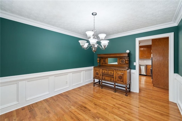 dining space with ornamental molding, a notable chandelier, and light hardwood / wood-style flooring