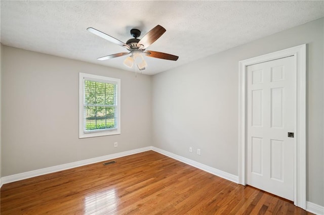 spare room with hardwood / wood-style flooring, ceiling fan, and a textured ceiling