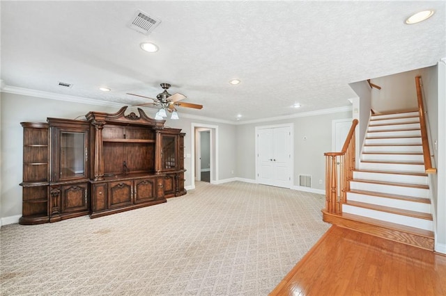 unfurnished living room featuring carpet floors, crown molding, a textured ceiling, and ceiling fan