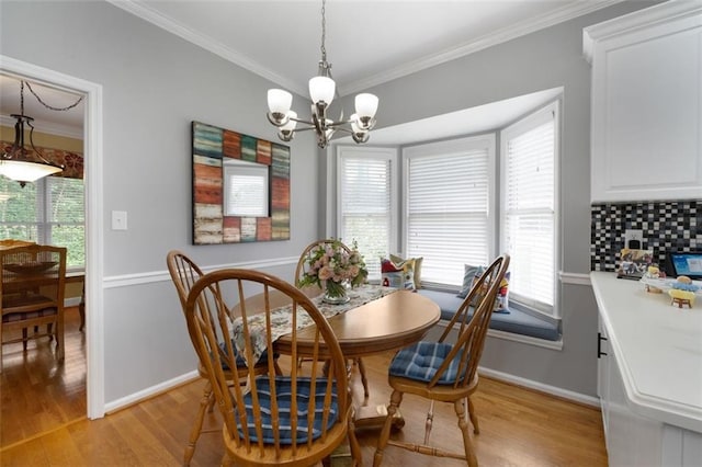 dining area with a chandelier, ornamental molding, light wood-type flooring, healthy amount of natural light, and baseboards