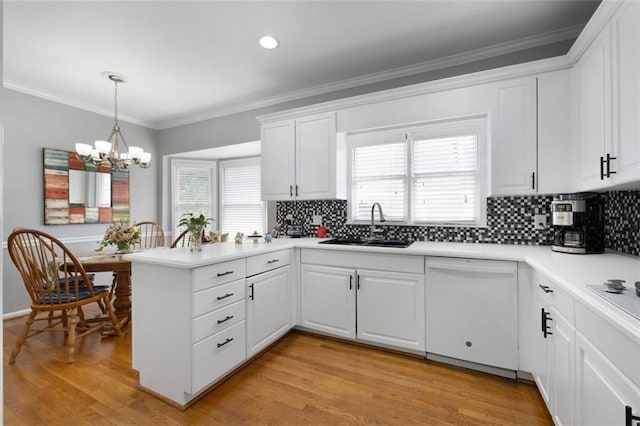 kitchen with dishwasher, a peninsula, decorative backsplash, a sink, and white cabinetry