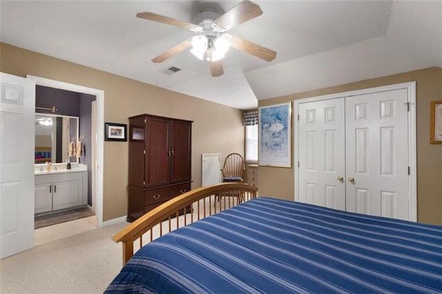 bedroom featuring light colored carpet, a closet, a sink, a ceiling fan, and connected bathroom