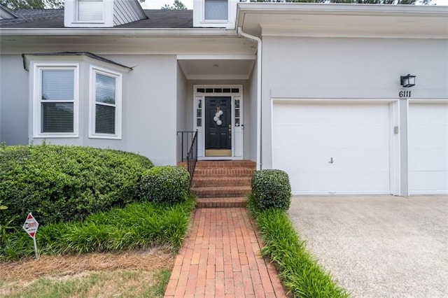 property entrance featuring a garage, stucco siding, and driveway