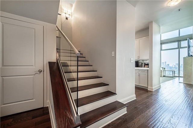 staircase with dark wood-type flooring and a wall of windows