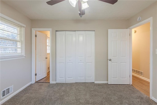 unfurnished bedroom featuring carpet floors, a closet, and ceiling fan