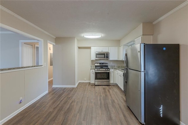 kitchen with crown molding, white cabinetry, light hardwood / wood-style flooring, stainless steel appliances, and light stone counters