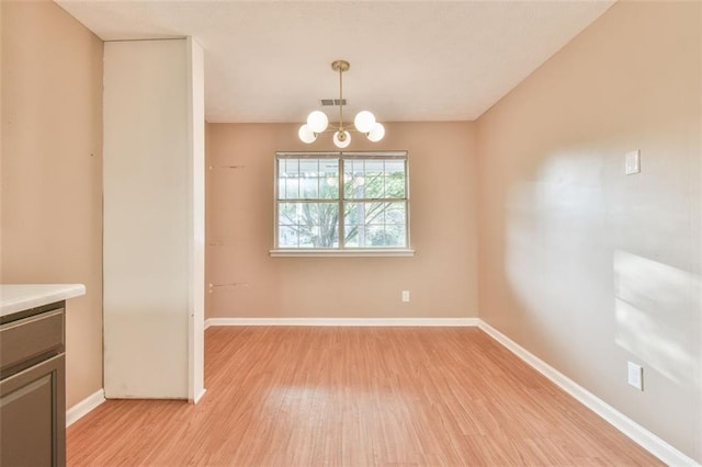 unfurnished dining area with light wood-style floors, visible vents, a notable chandelier, and baseboards