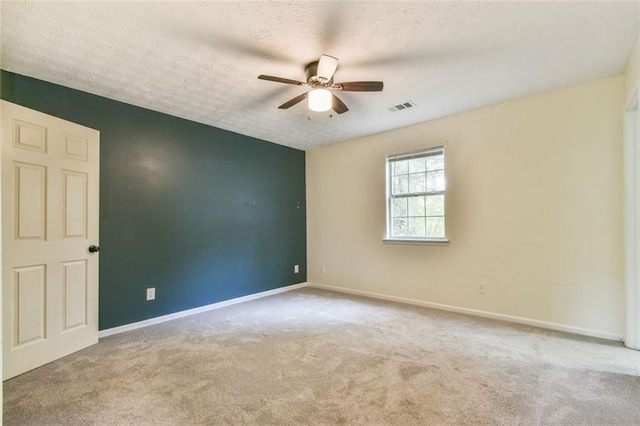 carpeted empty room featuring visible vents, a textured ceiling, baseboards, and ceiling fan