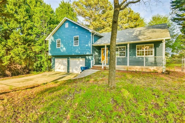 tri-level home featuring a front yard, an attached garage, fence, and driveway