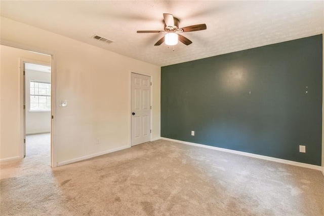 spare room featuring visible vents, carpet floors, baseboards, and ceiling fan