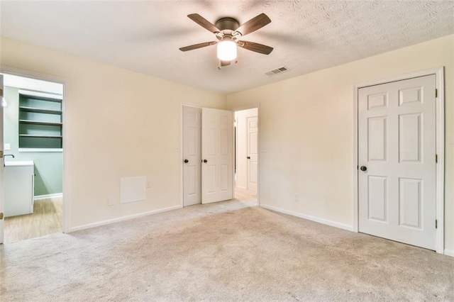 unfurnished bedroom with carpet, visible vents, baseboards, and ceiling fan