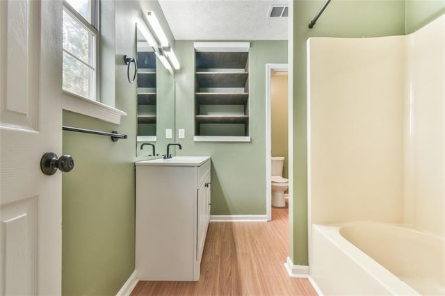 full bathroom featuring visible vents, baseboards, toilet, vanity, and wood finished floors