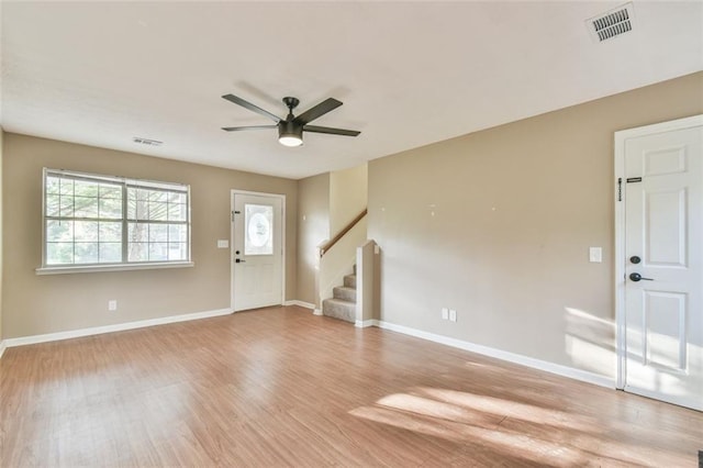 foyer entrance with baseboards, stairs, light wood-style floors, visible vents, and ceiling fan