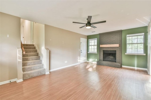 unfurnished living room with wood finished floors, baseboards, a ceiling fan, and plenty of natural light